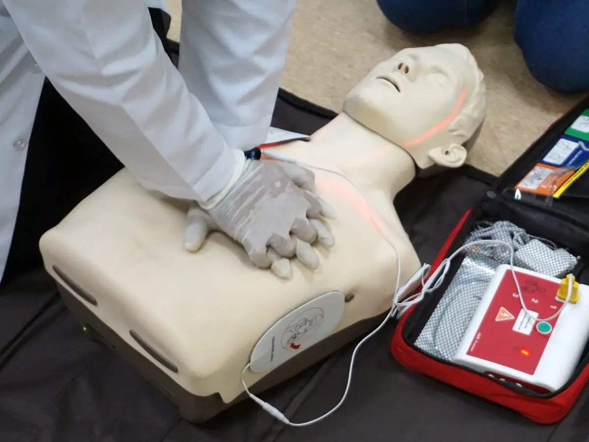 A Certified Instructor performing CPR on a dummy with an AED Machine