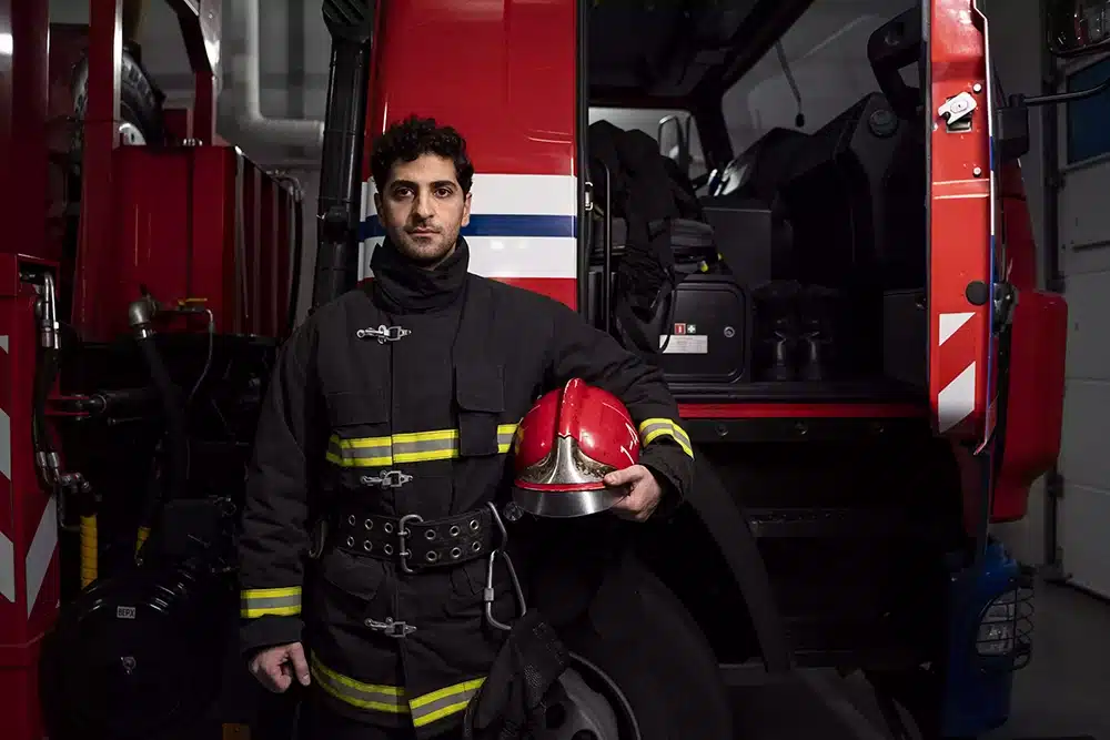 A Well-Trained Firefighter standing in front of a Fire-Truck