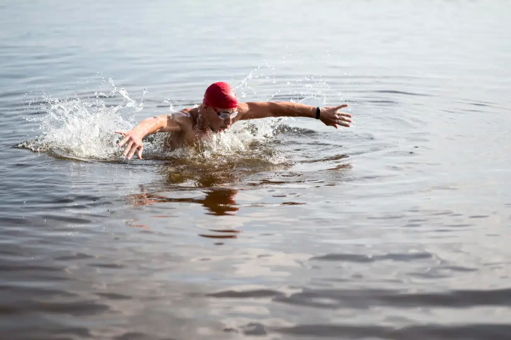 A person swimming in the lake without the lifejacket