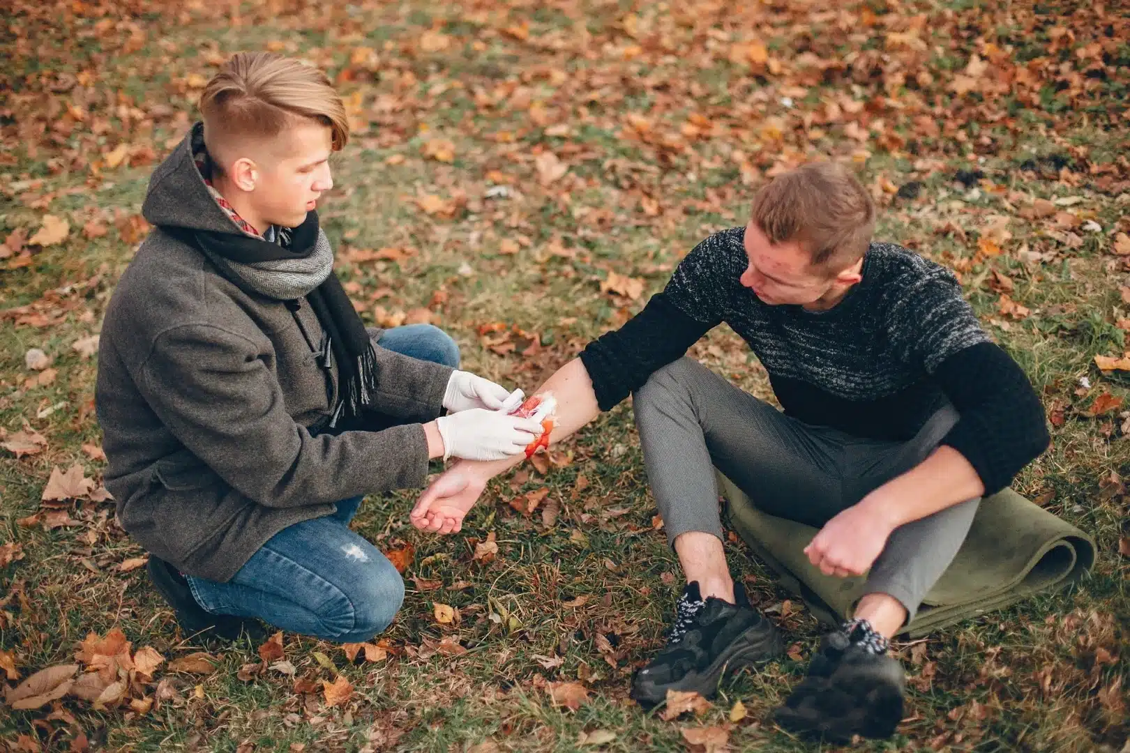 A person giving emergency first aid to someone in the park.