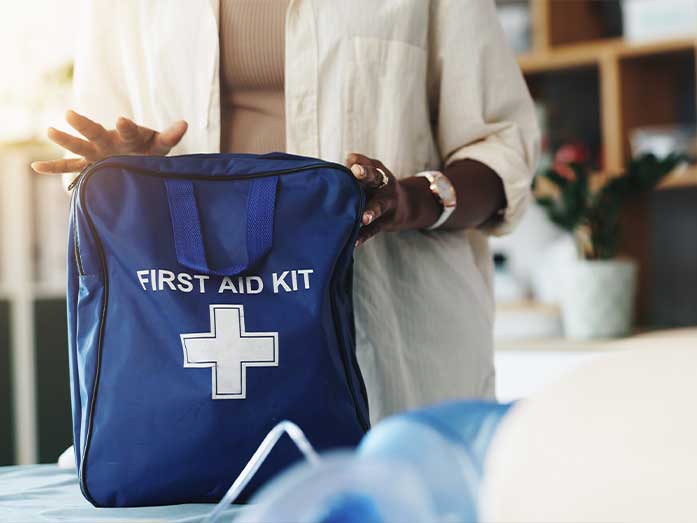 Person placing a blue first aid kit on a table, highlighting workplace safety and emergency preparedness supplies for office environments.