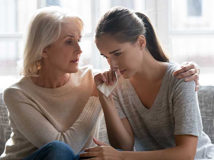 Older woman comforting a distressed young woman, representing psychological first aid support, mental health awareness, and emotional crisis intervention.